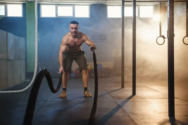 英俊强壮的男人在健身房用战斗绳做肌肉练习. — 图库照片