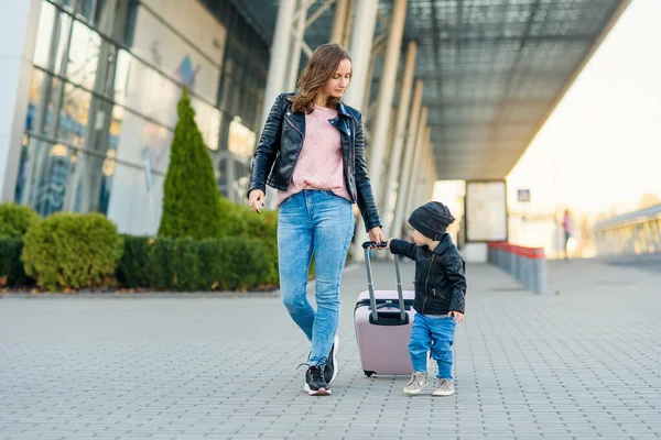 Piękna matka i jej stylowe cute córka chodzić razem i ciągnąć różową walizkę na lotnisko. — Zdjęcie stockowe