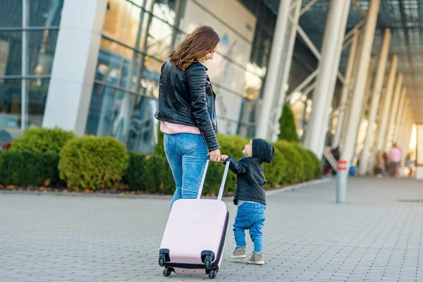 Piękna matka i jej stylowe cute córka chodzić razem i ciągnąć różową walizkę na lotnisko. — Zdjęcie stockowe