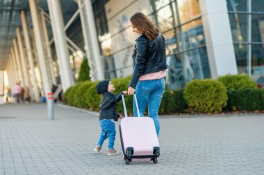 Güzel anne ve şirin kızı birlikte yürürler ve havaalanına pembe bir bavul çekerler..