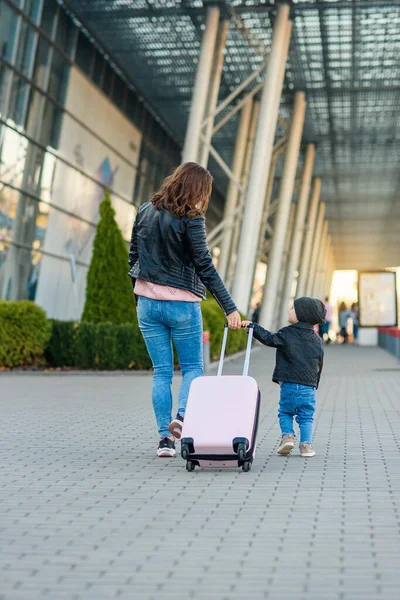 Piękna matka i jej stylowe cute córka chodzić razem i ciągnąć różową walizkę na lotnisko. — Zdjęcie stockowe