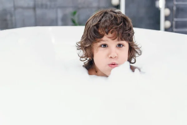 Смішний маленький хлопчик грає з піною у ванній . — стокове фото