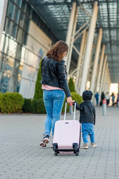 Bella madre e la sua elegante figlia carina camminare insieme e tirare una valigia rosa per l'aeroporto . — Foto Stock