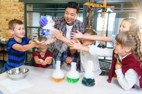 İlgilenen öğrenciler, cam şişelerdeki renkli sıvıların değişiminin kimyasal reaksiyonlarını inceliyor.. — Stok fotoğraf
