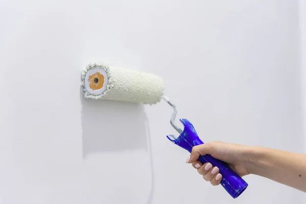 Painting out a white wall with a paint roller with white paint. Close up female hand painting wall with paint roller. — Stock Photo, Image