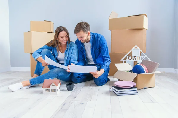 Feliz pareja alegre en el amor divertirse juntos en su propio nuevo piso después de quitar en el fondo cajas de cartón — Foto de Stock