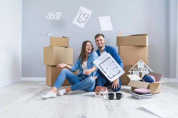 Feliz pareja alegre en el amor divertirse juntos en su propio nuevo piso después de quitar en el fondo cajas de cartón — Foto de Stock