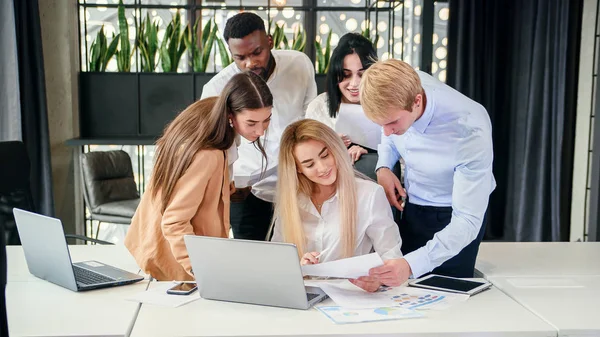 Erfolgreiches junges gemischtes Arbeitsteam analysiert Finanzberichte während ihrer Arbeit im Rahmen eines Gemeinschaftsprojekts am Vorstandstisch. Geschäfts- und Finanzkonzept. — Stockfoto