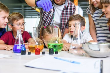 Renkli sıvı maddelerle test tüpleri. Sıvı durumları inceleyin. Test tüplü grup öğrencileri kimyasal sıvılar üzerinde çalışıyorlar. Bilim konsepti. Kızlar ve erkek sıvı deneyi yapıyorlar..