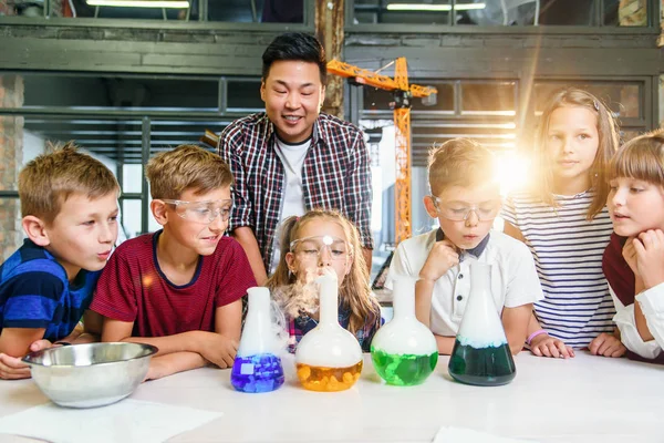Kimya dersi alan genç erkek öğretmenli öğrenciler çağdaş laboratuvar sınıfında kimyasal sıvılar ve kuru buz kullanarak ilginç deneyler yapıyorlar.. — Stok fotoğraf