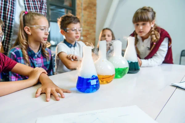 Genç öğrenciler renkli sıvılarda kimyasal reaksiyon sürecini ve test tüplerinde kuru buzu izliyorlar.. — Stok fotoğraf