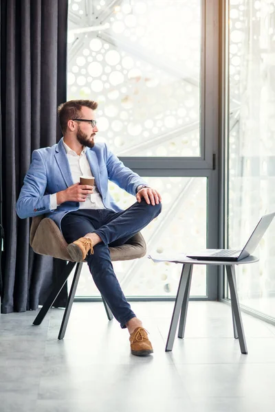 Empresário bem sucedido tem uma pausa descansando e bebe café perfumado na sala de escritório moderna. Jovem empresário bem sucedido . — Fotografia de Stock