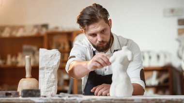Sakallı heykeltıraş, yaratıcı stüdyodaki kireçtaşından kopyasını yapmak için taş kadın gövdesini ölçer..