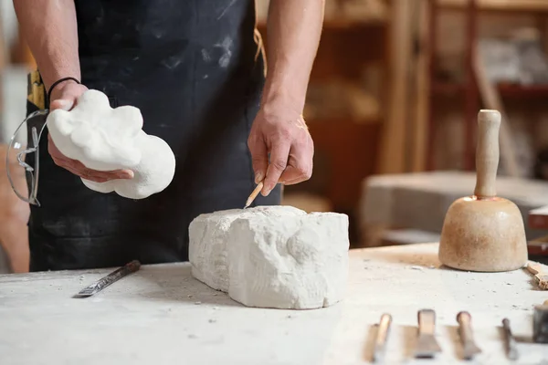 Manos masculinas trabajando con una piedra blanca. Escultor profesional talla escultura de piedra de piedra caliza . — Foto de Stock