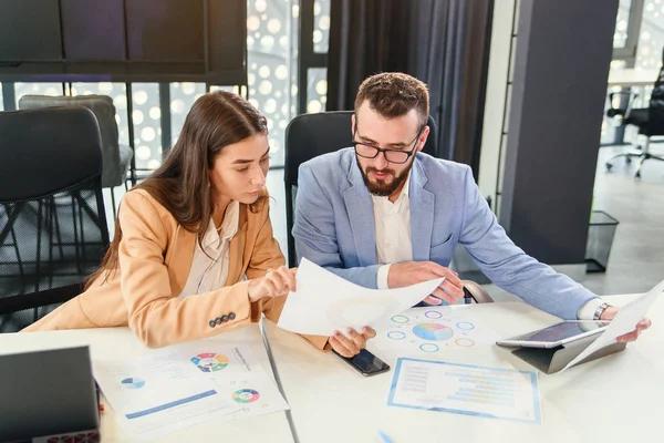 Socios comerciales interesados en estudiar cuidadosamente los documentos financieros con gráficos en la mesa de juntas en la sala de reuniones . — Foto de Stock