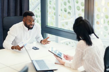 Sempatik iş ortakları toplantı odasındaki toplantı masasında haritalarla finansal belgeleri dikkatle inceliyor..