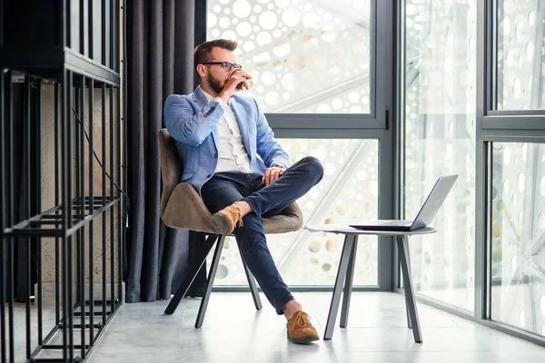 Framgångsrik affärsman har en paus vila och dricker doftande kaffe i moderna kontorsrum. Framgångsrik ung affärsman. — Stockfoto