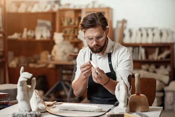 Professional sculptor holds in hands fresh handmade gypsum mold and looks at final results of his work after removing from the silicone mold.