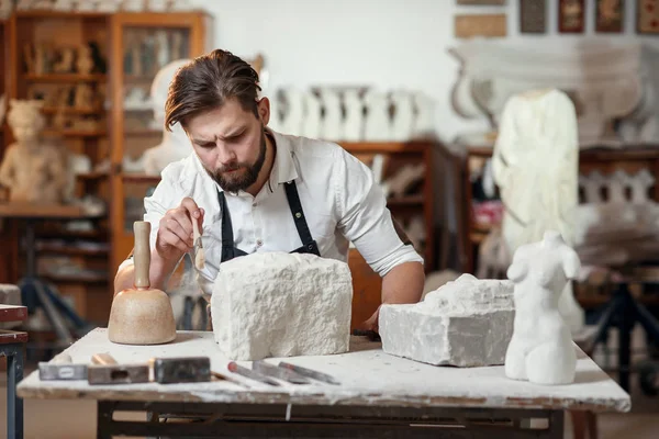 Stonemason, amely ül a kreatív műhelyben, és kaparja a maradványait mész-kő ecsettel — Stock Fotó