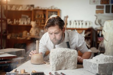Atmosferik stüdyodaki yaratıcı iş yerinde taş heykeltıraşla çalışan usta elleri..