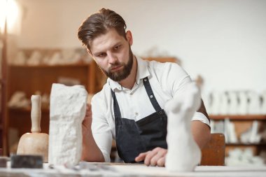 Sakallı heykeltıraş, yaratıcı stüdyodaki kireçtaşından kopyasını yapmak için taş kadın gövdesini ölçer..