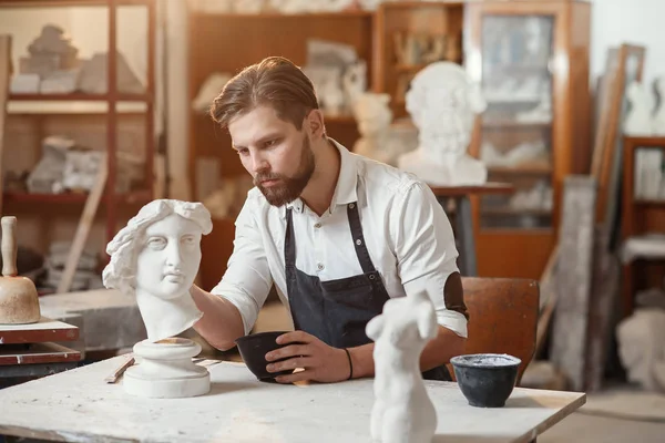 Skillful sculptor makes professional restauration of gypsum sculpture of womans head at the creative workshop. — Stock Photo, Image