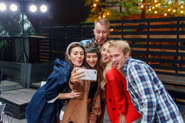 Neşeli şık arkadaşlar partide selfie çekiyorlar. Herkes gülümsüyor ve arkadaşlıklarının tadını çıkarıyor..