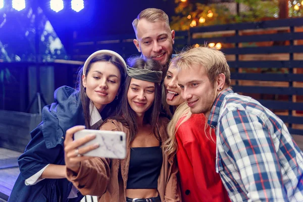 Amigos alegres y elegantes haciendo selfie juntos en la fiesta. Todos sonríen y disfrutan de su compañía . — Foto de Stock
