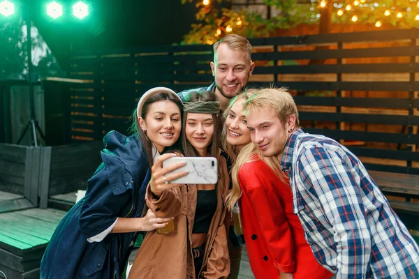Amigos alegres y elegantes haciendo selfie juntos en la fiesta. Todos sonríen y disfrutan de su compañía . — Foto de Stock
