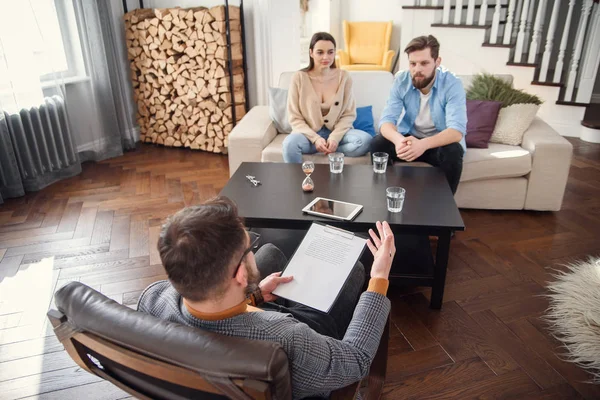 Geïrriteerde blanke paar man en vrouw in gesprek met psycholoog op therapie sessie in lichte kamer. — Stockfoto