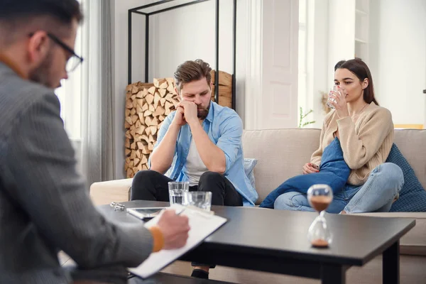 Annoyed caucasian couple of man and woman having conversation with psychologist on therapy session in light room. — Stock Photo, Image