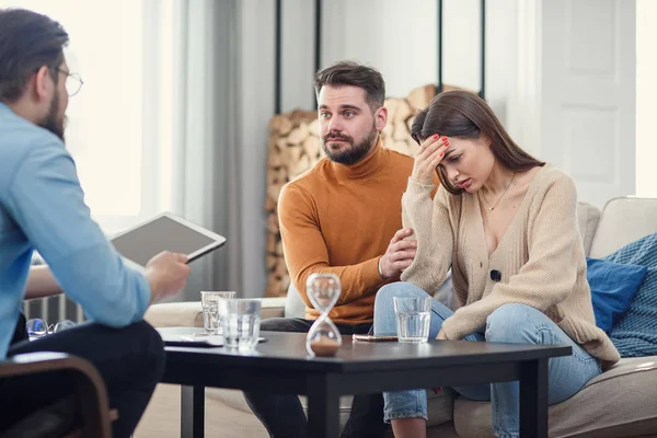 Molesto pareja caucásica de hombre y mujer teniendo conversación con el psicólogo sobre la sesión de terapia en la sala de luz . — Foto de Stock