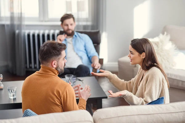 Depressed young couple of man and woman speaking with psychologist on therapy session in modern office. Bad relationships without future. — Stok fotoğraf