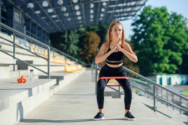 Νεαρή σπορ γυναίκα κάνει ασκήσεις με λαστιχένια ζώνη εξωτερική — Φωτογραφία Αρχείου
