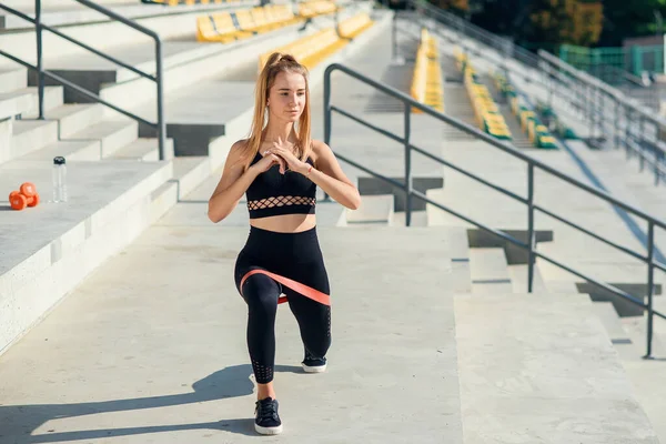 Junge sportliche Frau macht Übungen mit Gummiband im Freien — Stockfoto