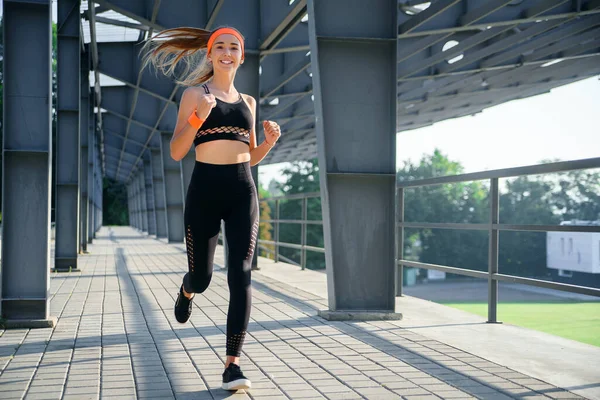 Junge Athletin läuft in Stadionnähe. — Stockfoto