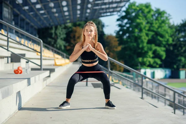 Genç sportif kadın lastik bantla dışarıda egzersiz yapıyor.