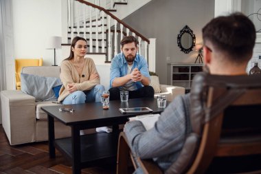 Erkek psikoloğun kapanışı koltukta oturur ve şık rahat ofisteki depresif genç çifti dinler. Seçici odak.