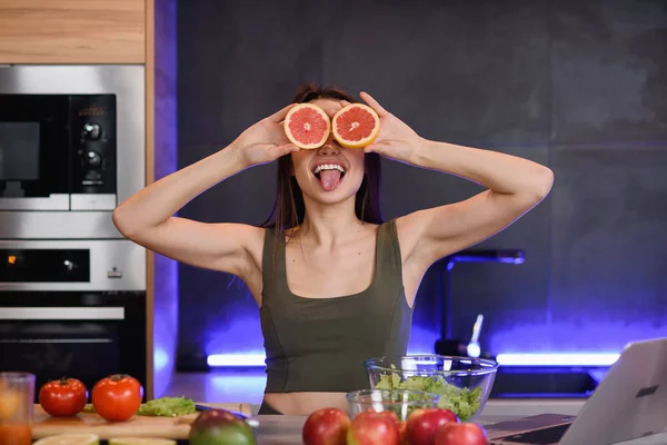 Funny and joyful young woman holding orange slices near her eyes and smiling. — Stock Photo, Image