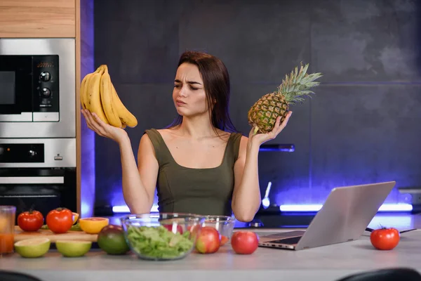 Kobieta, wybór między deser i owoce na stole w kuchni. Zdrowa dieta — Zdjęcie stockowe