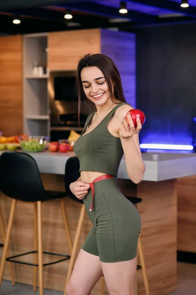 Красивая спортивная женщина с яблоком и мерной лентой — стоковое фото