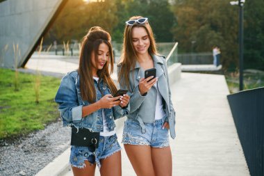 Kız arkadaşlar sabah şehirde yürürken akıllı telefon kullanırlar. Kadın blogcular Avrupa 'ya seyahat ediyor. Modern iletişim akıllı teknolojiler ve arkadaşlık kavramı.