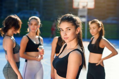 Spor eğitimini şehir parkındaki özel donanımlı spor alanında bitirdikten sonra kameraya bakan çekici, güler yüzlü, ince bayanın ön görüntüsü.