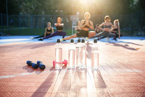 Fitness, deporte, entrenamiento, gimnasio y concepto de estilo de vida - grupo de mujeres con botellas de agua en el gimnasio — Foto de Stock