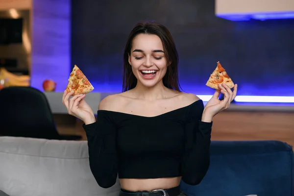 Chica hermosa feliz con sonrisa perfecta divirtiéndose con pizza en casa. La mujer cena, disfruta de la comida. Concepto de ocio . — Foto de Stock