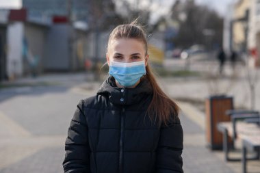 Dışarıda akıllı telefon kullanan koruyucu maskeli ve eldivenli bir kız. COVID 19. Dünya koronavirüs salgını.