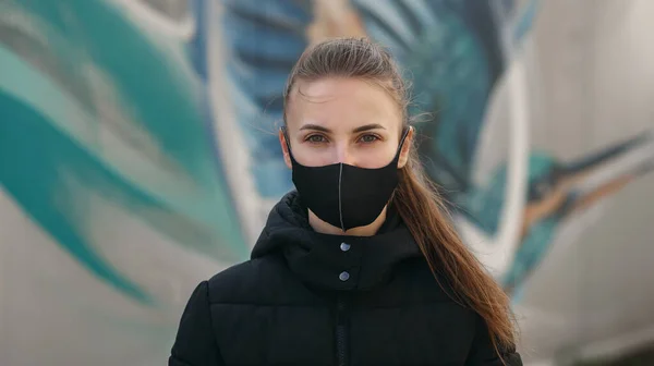 Menina na rua da cidade vestindo máscara facial médica estéril preto. Mulher usando o telefone para procurar notícias sobre o nCov 2019. Quarentena COVID-19 epidemia de coronavírus pandêmico e conceito de cuidados de saúde — Fotografia de Stock