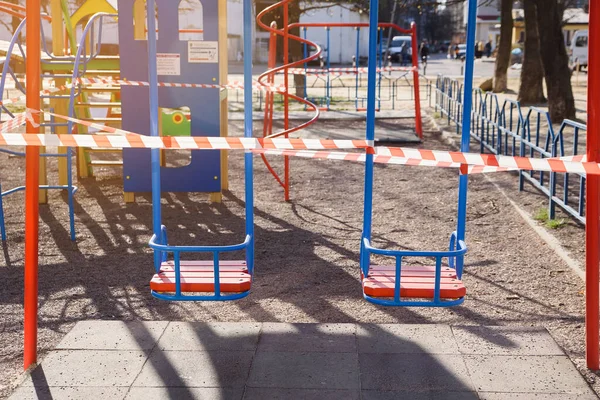 Childrens playground closed and wrapped in alarm caution tape for global coronavirus quarantine.No children on playgrounds. Prevention of coronavirus COVID-19.