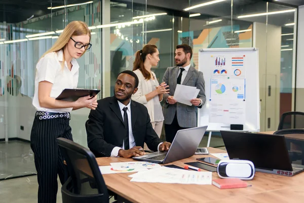 Attraktive Mitarbeiterin berät sich mit ihrem Büroleiter und unterschreibt Finanzdokumente an ihrem Arbeitsplatz. — Stockfoto