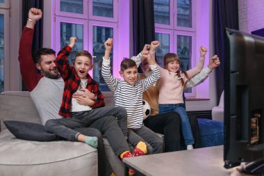 Aile futbol maçı izliyor, şampiyonluk maçı evdeki kanepede. Favori milli takım için duygusal tezahüratlar. Babaları ve büyükbabaları olan çocuklar evde eğleniyorlar..